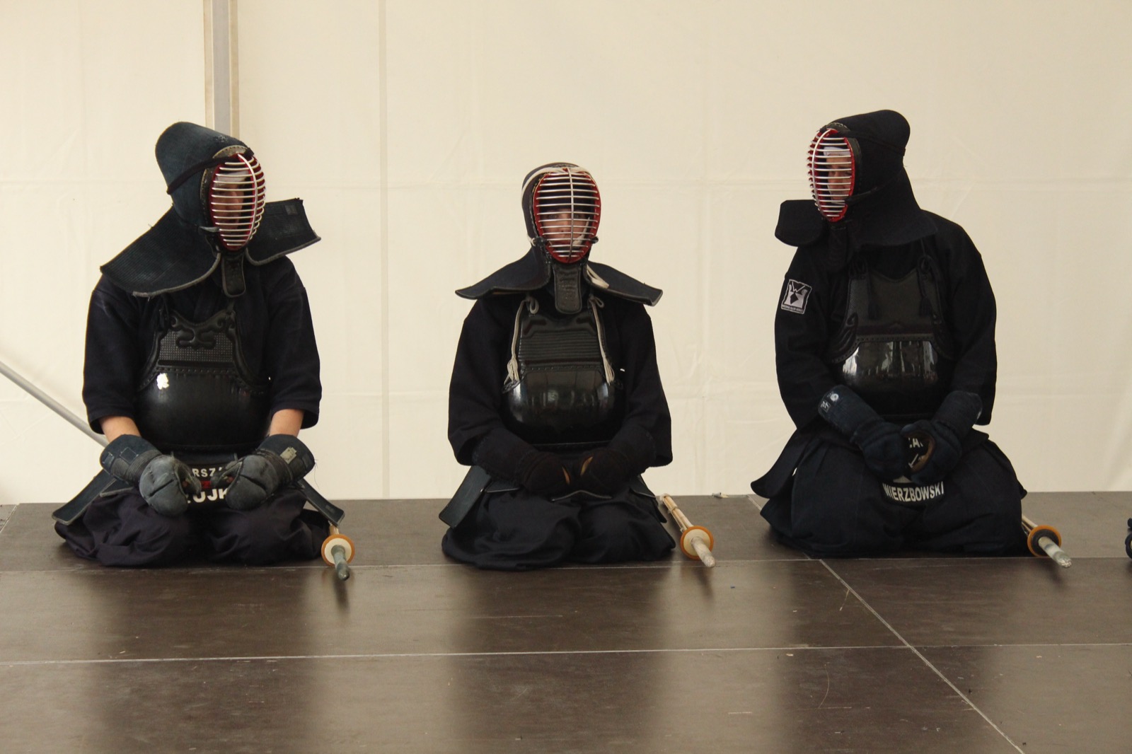 剣道の防具を着けた3人が竹刀を前に置いて正座している様子
