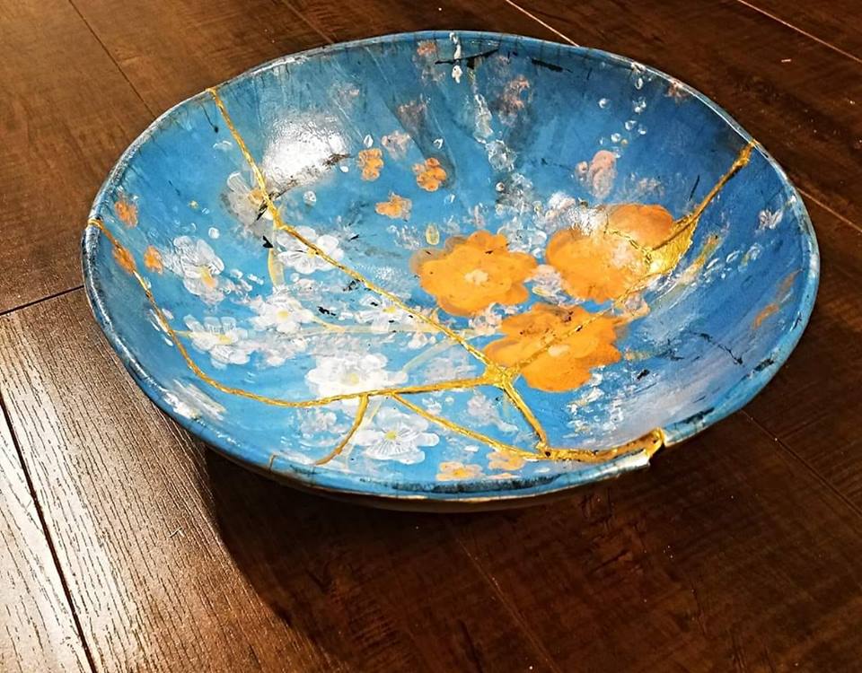 A ceramic bowl repaired with visible seams of gold lacquer