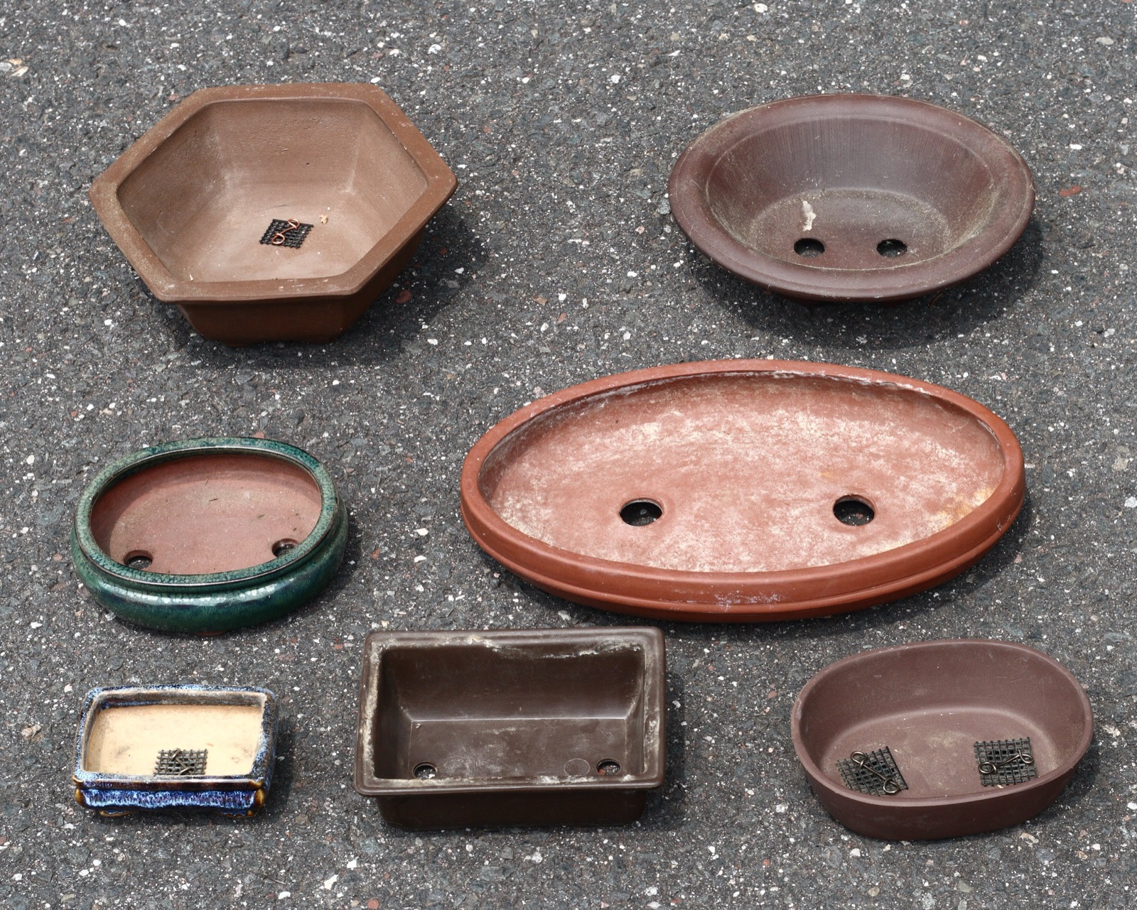 A group of bonsai pots in varied shapes, colors, and glazes