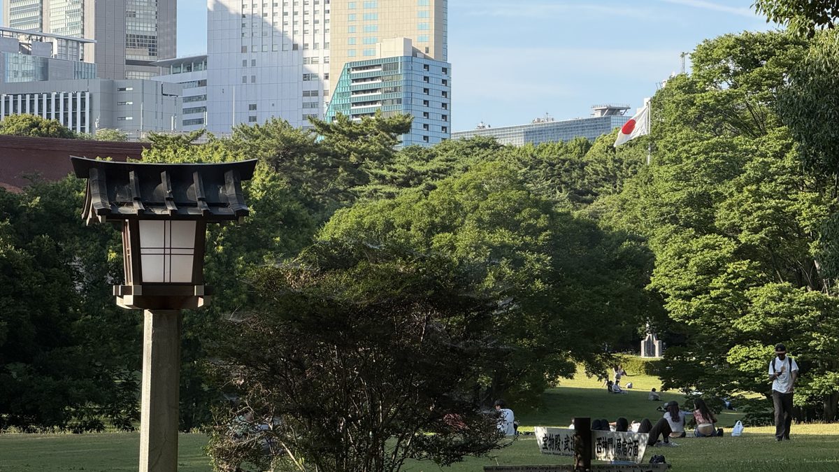 Green space and a stone lantern against the Tokyo skyline